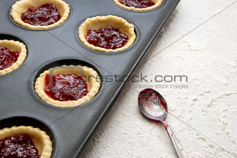 Filled, uncooked jam tarts in a tin