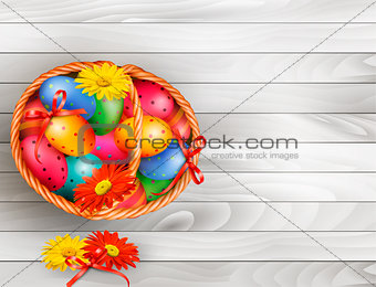 Easter background with color easter eggs in basket on wooden tab