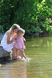 mother and her little daughter squirt water at the lake