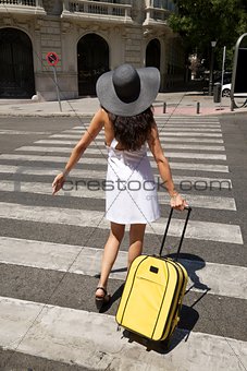 woman back stand on crosswalk with suitcase 
