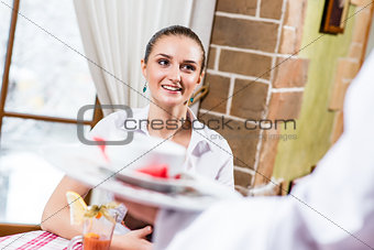 waiter brings a dish for a nice woman