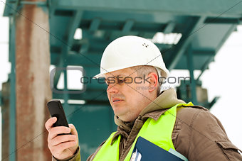 Engineer with cell phone on a transformer background