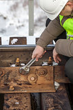 Railroad worker with wrench fix the nut on the bridge