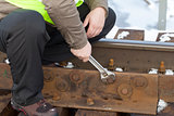 Railroad worker with wrench on the railway bridge fix the nut