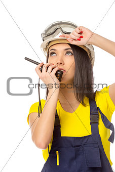Serious female construction worker talking with a walkie talkie 
