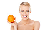 Smiling girl is holding fresh orange