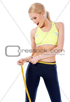 Surprised blond sporty woman measuring her waist