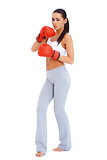 Full body shot of a woman wearing boxing gloves