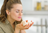 Young housewife smelling mushroom in kitchen