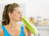 Young woman smelling celery in kitchen