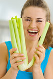 Smiling young woman holding celery