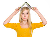 Confused student girl with raised book over head