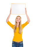 Happy student girl holding blank board over head