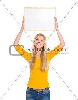 Happy student girl holding blank board over head