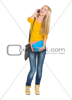 Full length portrait of smiling student girl talking mobile phon