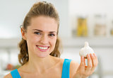 Smiling young housewife showing garlic