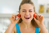Smiling young woman using cherry tomato as earrings
