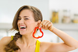 Happy young woman using slice of bell pepper as earring