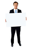Portrait of businessman showing blank signboard