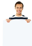 Casual young man holding a blank poster