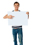Portrait of young man pointing at blank signboard
