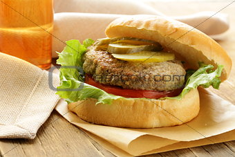 burger with tomatoes and pickled cucumbers on a wooden table