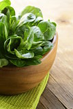 Fresh green salad valerian in a wooden bowl