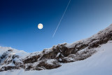 Full Moon and Airplane Trail in Blue Sky above Mountain Peak, Fr