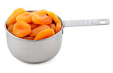 Whole dried apricots presented in an American metal cup measure