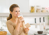 Young woman eating crisp bread with milk and looking on copy spa