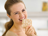 Happy young woman eating crisp bread