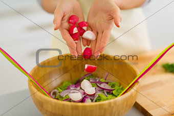 Closeup on housewife adding radishes into vegetable salad