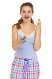 Surprised young woman in pajamas with TV remote control