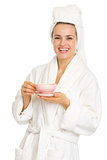 Happy young woman in bathrobe with cup of coffee