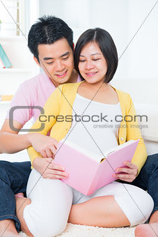 Asian pregnant couple reading book 