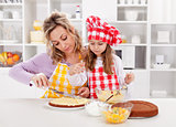 Mother and little girl making a cake together