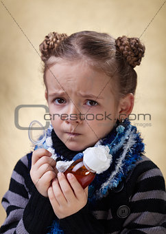 Little girl with cough medicine having a worried look