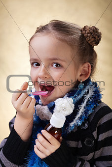 Little girl taking cough medicine syrup