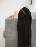 Young woman with long black hair laying on divan in living room