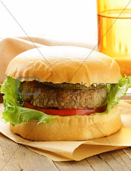 burger with tomatoes and pickled cucumbers on a wooden table