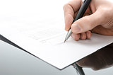 Male hand signing a contract on a black table