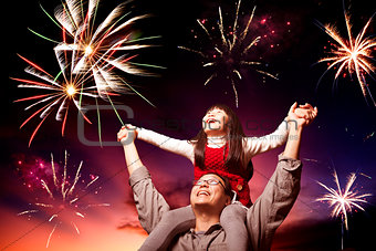 father and daughter looking fireworks in the evening sky