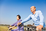 Happy elderly seniors couple biking 