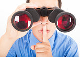 man looks through binoculars with silent gesture