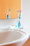 Colorful toothbrushes in a glass in bathroom