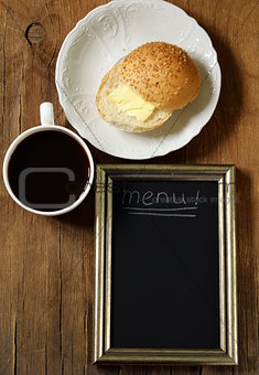 Coffee cup and bun with butter with  slate chalk board