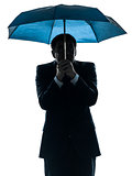 anxious business man under umbrella silhouette