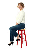 Confident senior woman resting on stool
