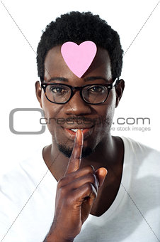 Man with pape heart on forehead gesturing silence