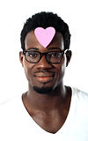 Closeup of an african man with pink paper heart on forehead
